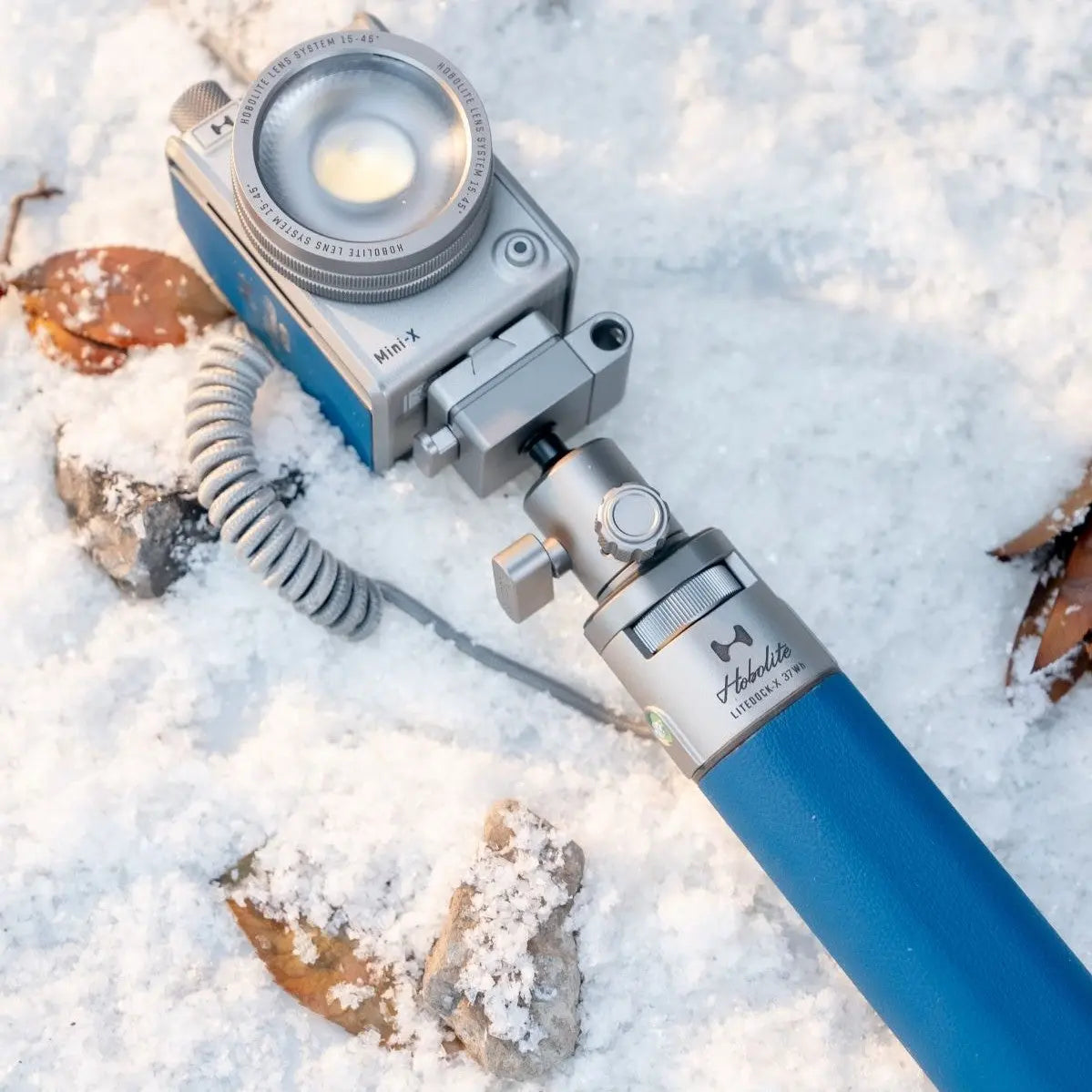 Hobolite Mini-X LED light on snow-covered rocks, showing compact design and durability in extreme cold.