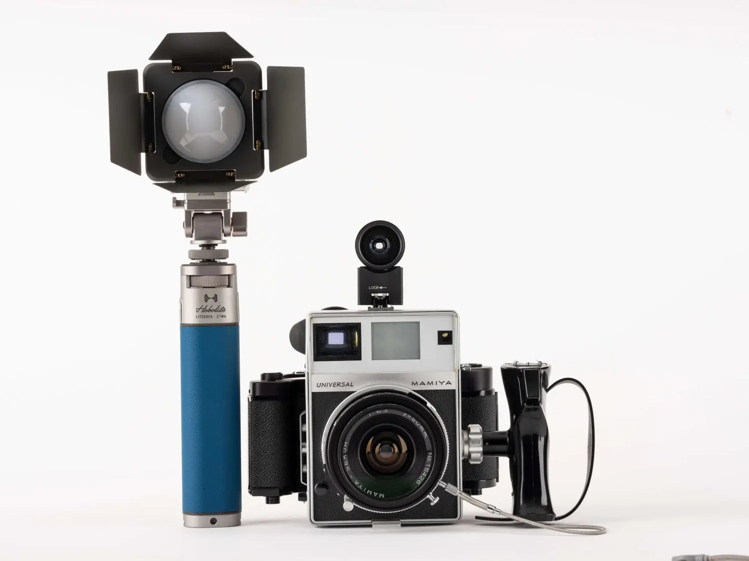 Hobolite LiteDock-X photography light with barn doors next to Mamiya camera on white background.