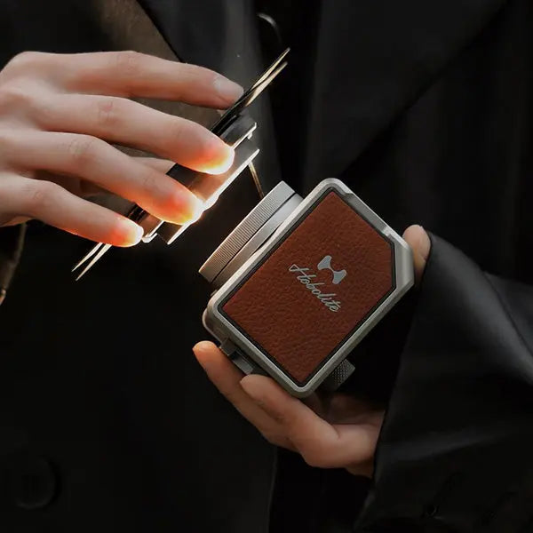 Hobolite Micro 8W portable LED light with silver frame and brown leather panel, held to show its compact design and illumination.