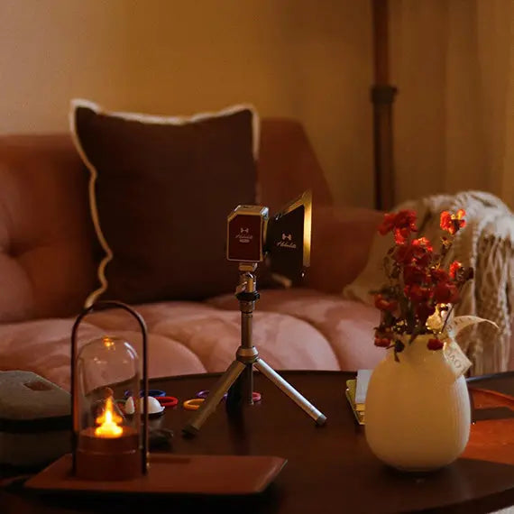 Hobolite Micro portable LED light on tripod in a cozy living room setting with flowers and a sofa.