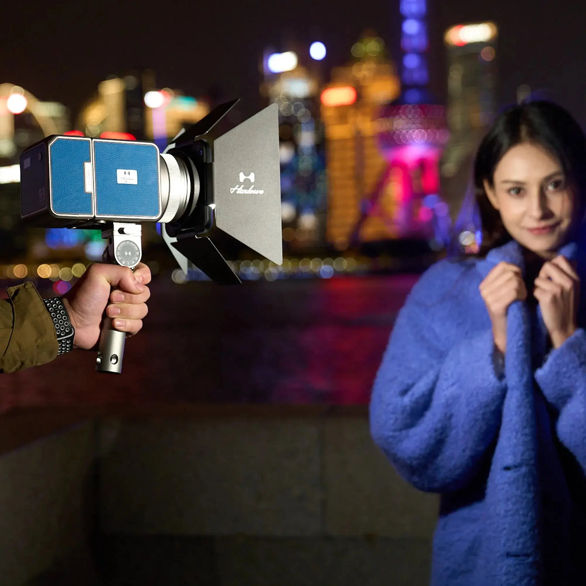 Max-X 80W LED light kit in use at night, illuminating a model in a blue coat against a vibrant urban city backdrop.