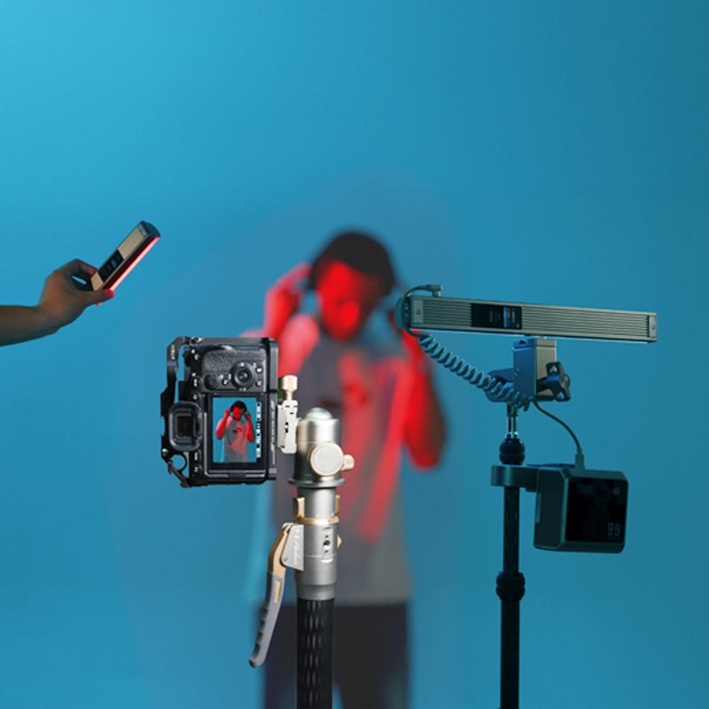 Harlowe Blade RGB tube lights in professional camera setup with camera, tripod, and creative red and blue lighting effects.