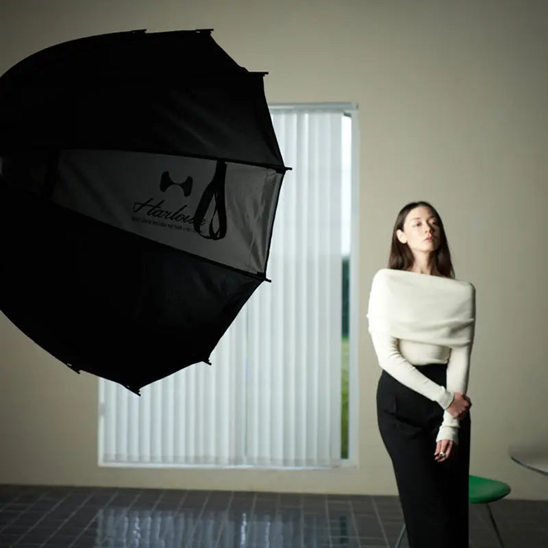 Harlowe deep softbox lighting unit illuminates a model posing in a studio with vertical blinds.