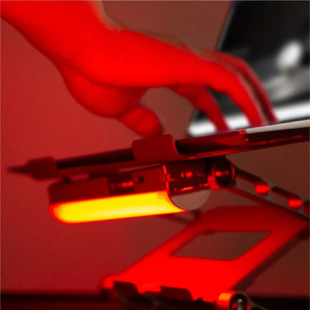Harlowe Blade RGB tube light with yellow-orange glow against dramatic red-tinted product photography setup.