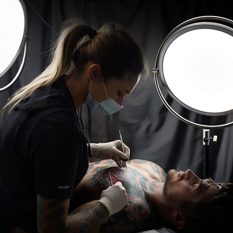 Harlowe Sol 100W LED panel light illuminating precise tattoo work with professional soft lighting.
