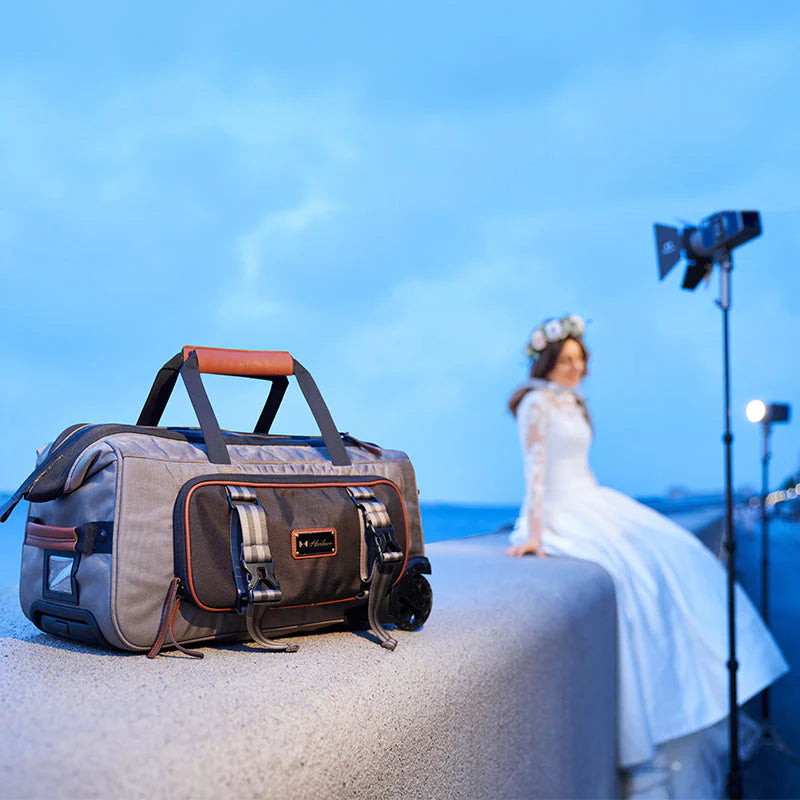 Harlowe travel lighting kit bag beside a bride being photographed at golden hour with an off-camera LED light setup