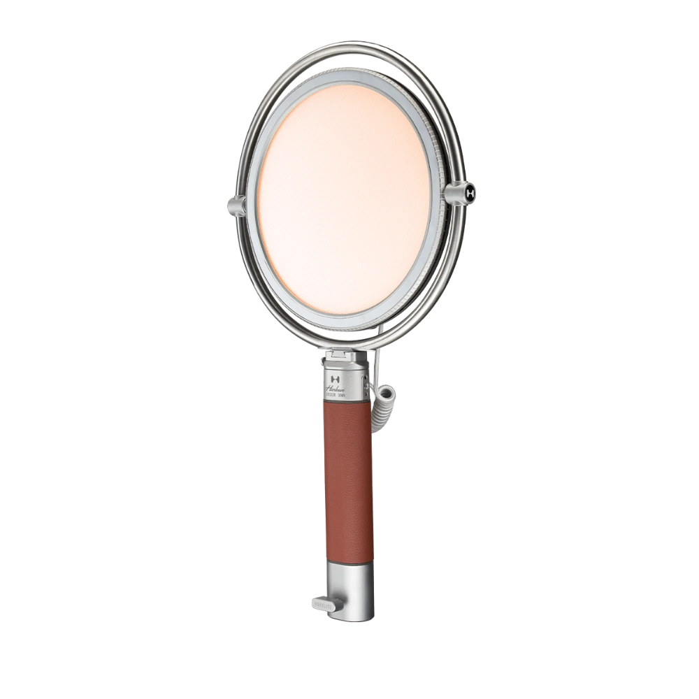 Harlowe Sol 40W round LED panel light with silver frame, warm diffusion, and brown leather handle on black background.