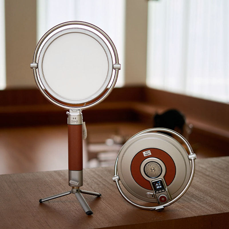 Harlowe Sol 40W round LED panel light with silver frame and brown leather handle on tripod.