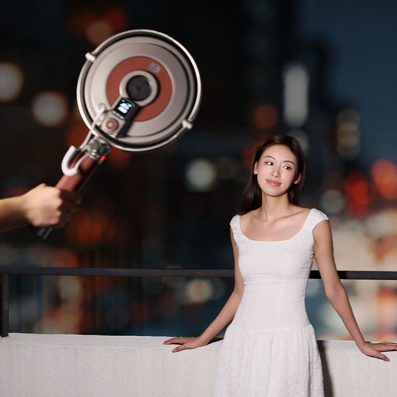 Harlowe Sol LED panel light illuminates woman in white dress with bokeh city lights background.